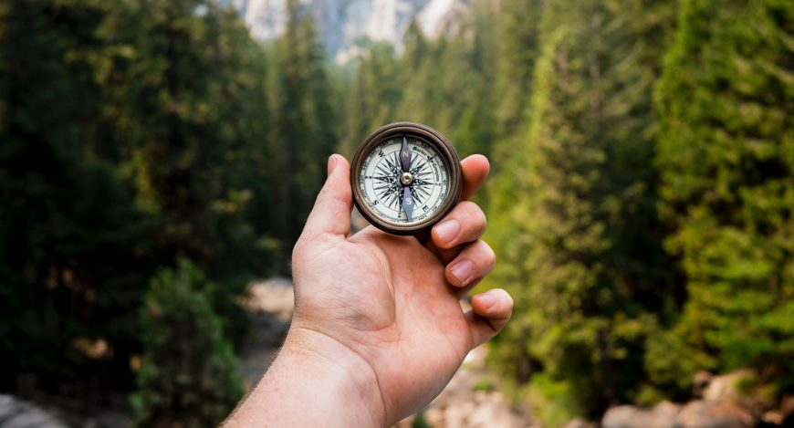 man holding compass in the woods